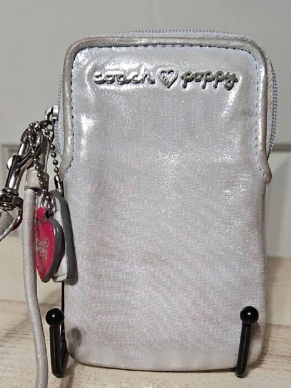 Silver Coach Poppy metallic silver leather phone wristlet featuring heart charm